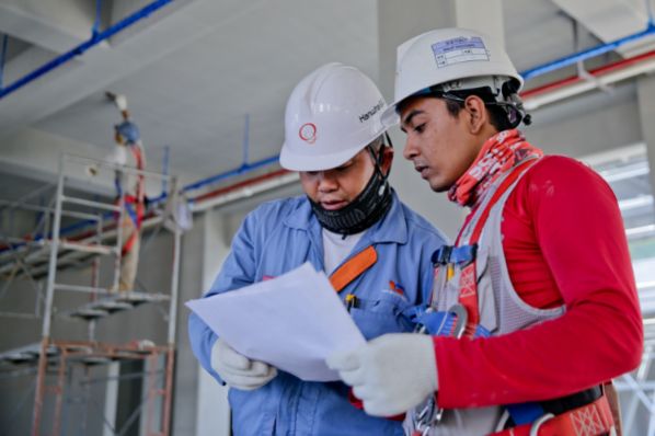 Dos hombres en un sitio de construcción consultando un documento